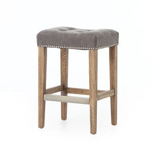 A gray upholstered linen bar stool with tufted backrest and nailhead trim, featuring a natural wood frame and legs.