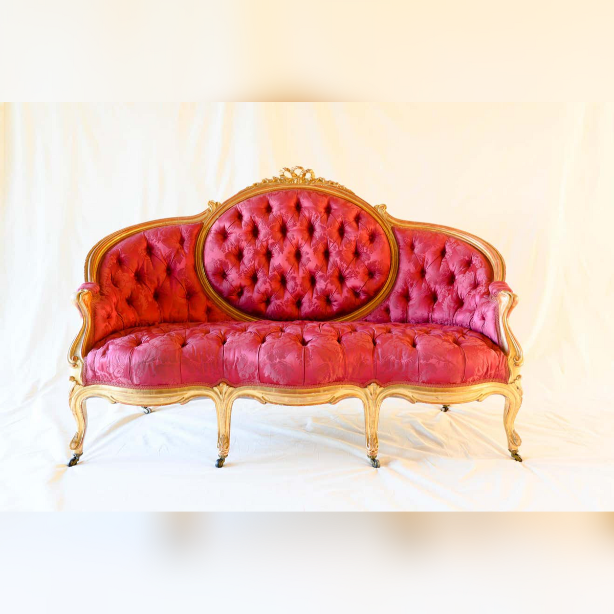 Pink tufted sofa with gold frame on a white background