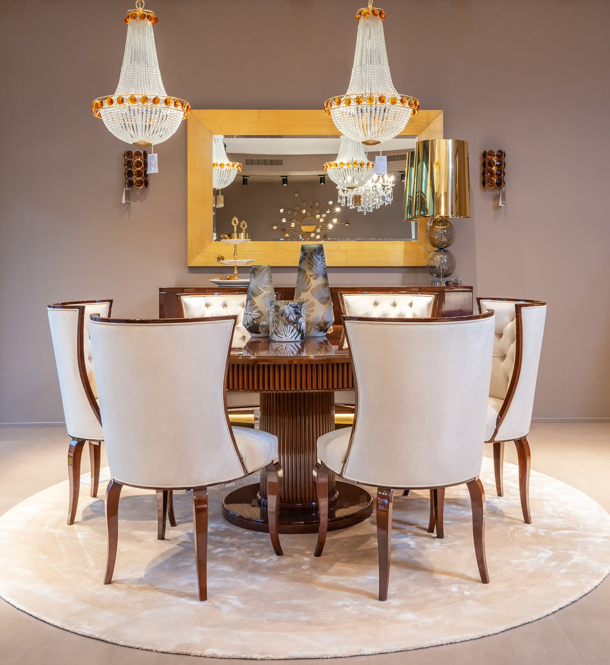Dining room with a wooden table, white chairs, and decorative chandeliers.