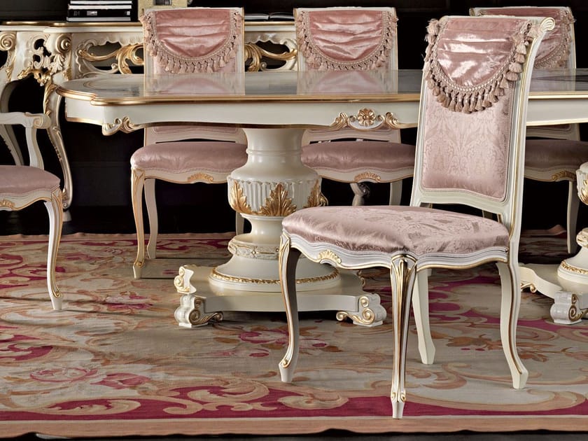 Elegant dining table set with ornate chairs on a patterned rug.