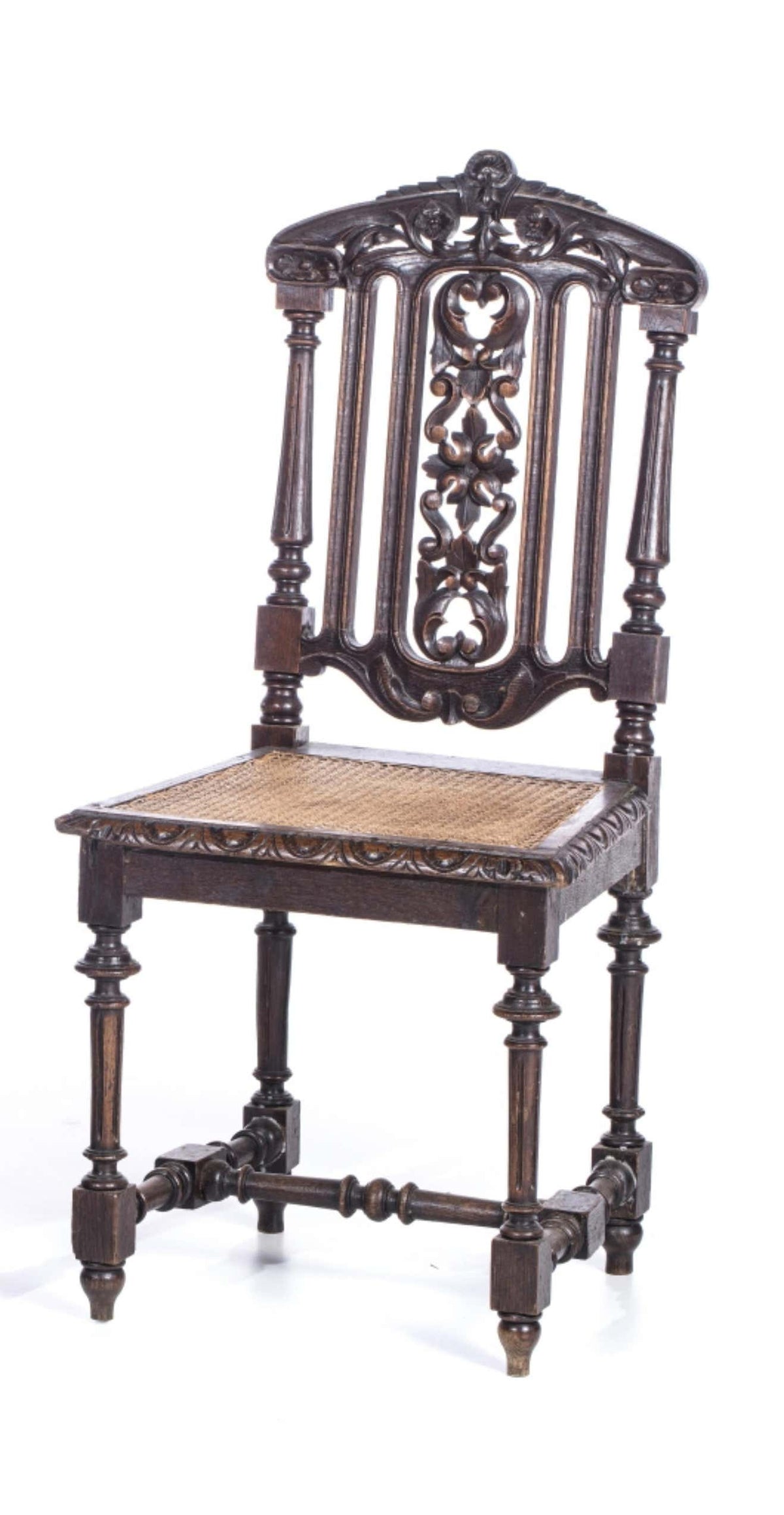 A handcarved wooden chair with intricate designs and a natural bamboo seat, featuring an antique black finish.