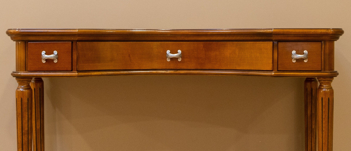 Wooden console table with three drawers against a beige wall