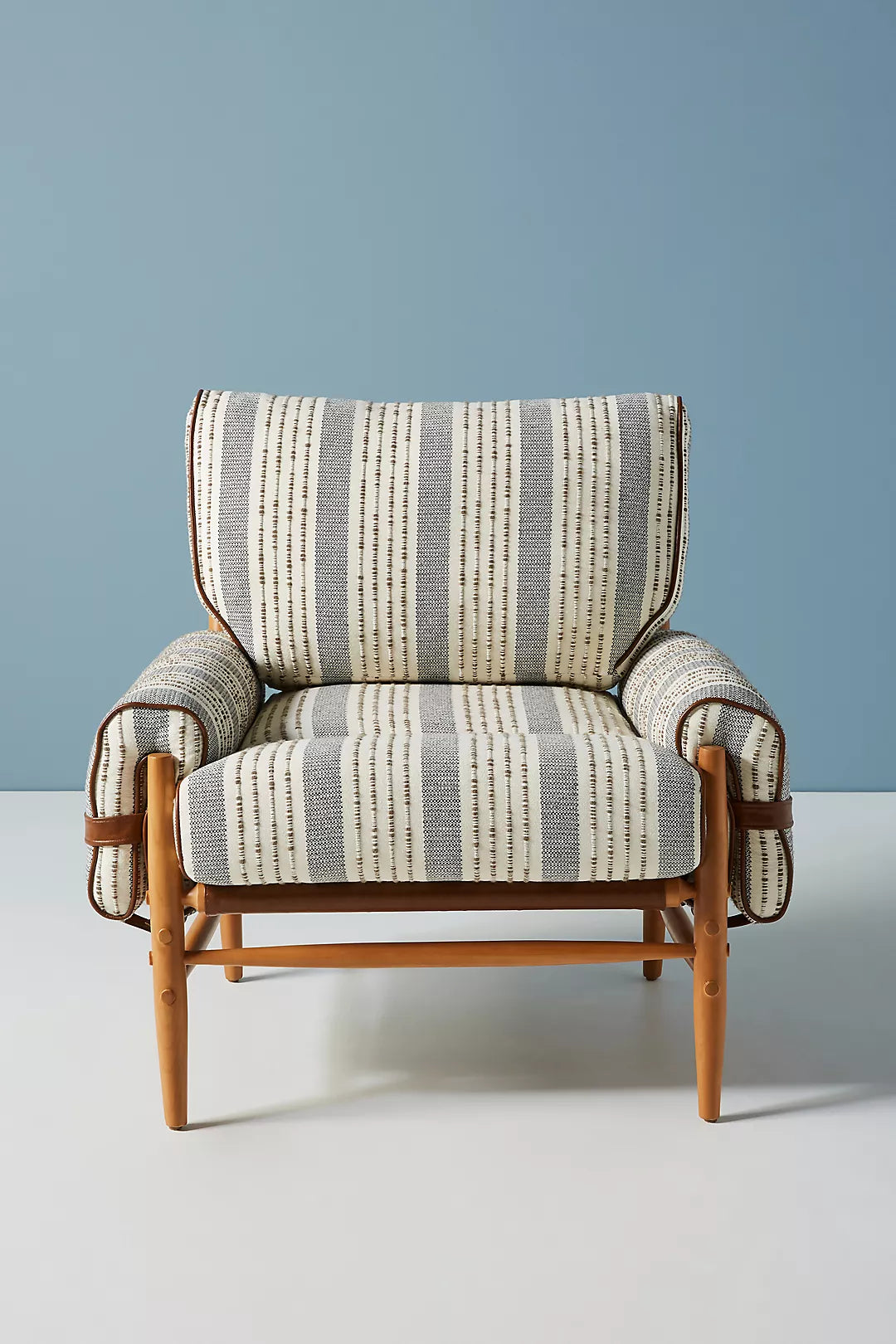 Striped armchair with wooden frame against a blue wall