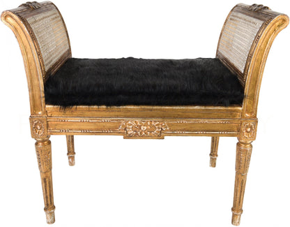 Antique gold finish bench with intricate cane work on the sides and a black upholstered seat