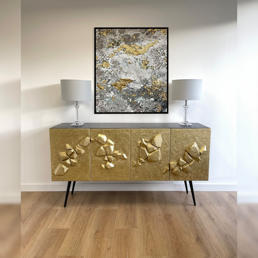 Gold decorative cabinet with abstract art and lamps in a room setting