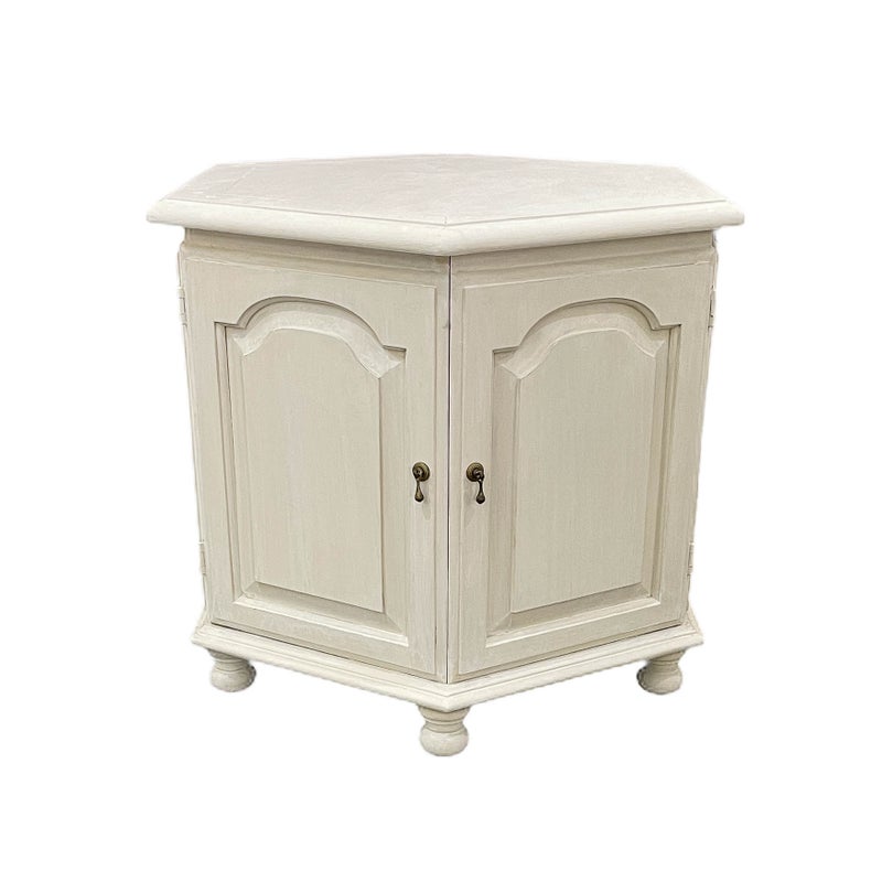 An ivory-colored hexagonal settee with a single drawer and two doors, featuring a classic design with a French distressed finish.