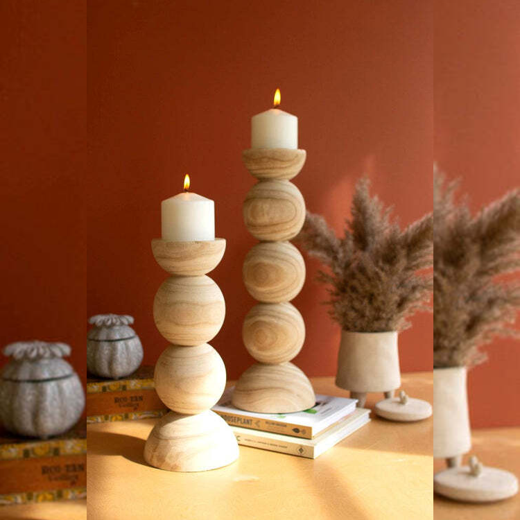 Wooden candle holder with a candle on a table against a red wall