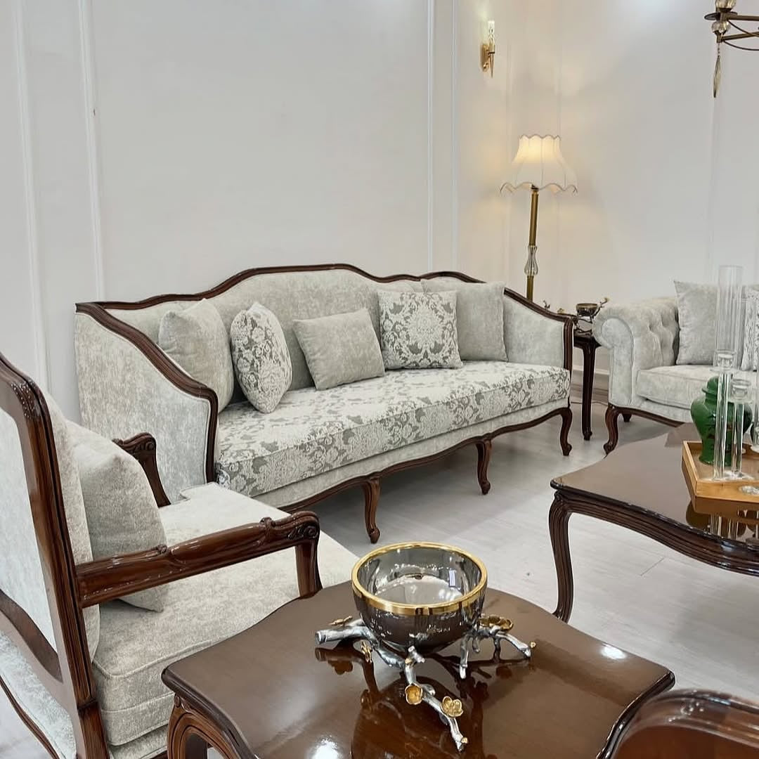 Living room with floral-patterned sofa and matching armchair, coffee table with decorative items.