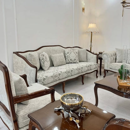 Living room with floral-patterned sofa and matching armchair, coffee table with decorative items.