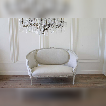Vintage-style sofa in a room with a chandelier and paneled walls.