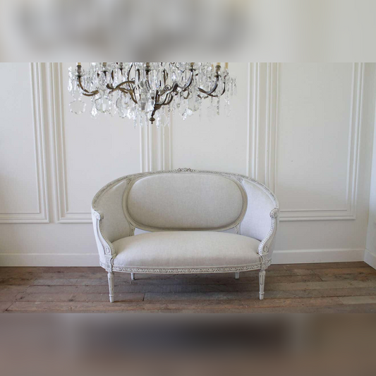 Vintage-style sofa in a room with a chandelier and paneled walls.