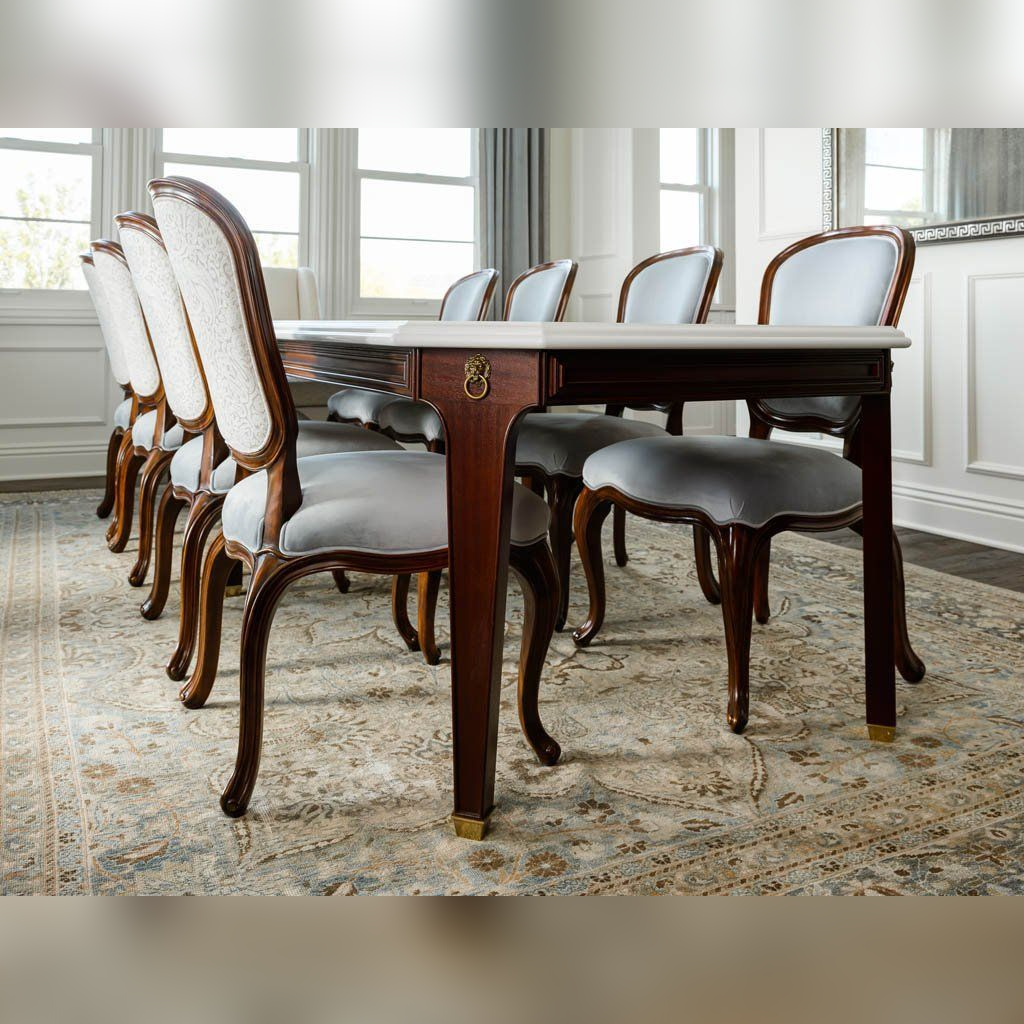 Dining table with chairs in a room with large windows and white walls.