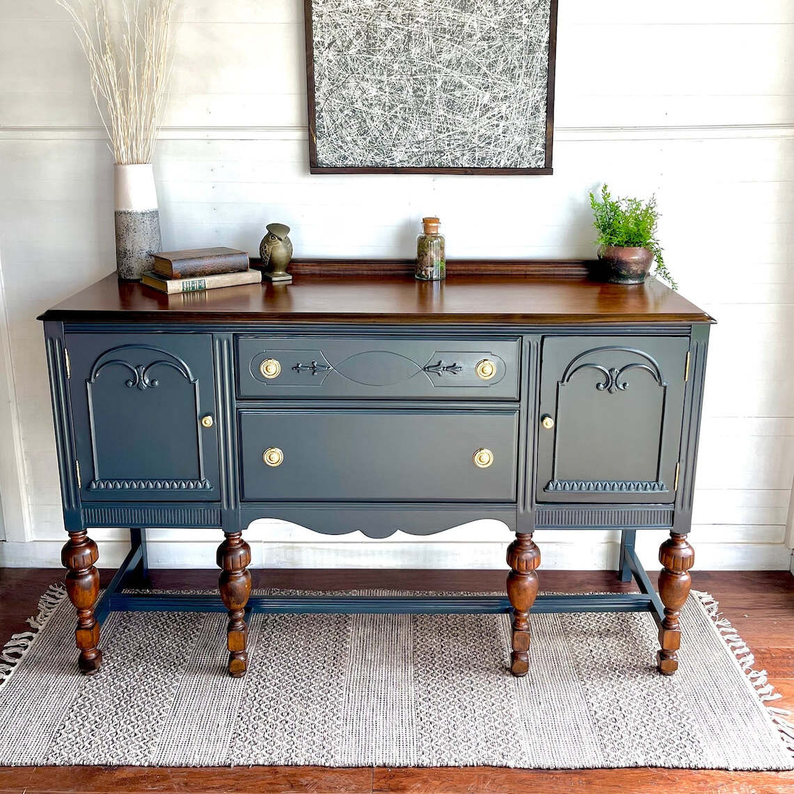 Dark gray sideboard with wooden accents in a room with a rug and wall art.