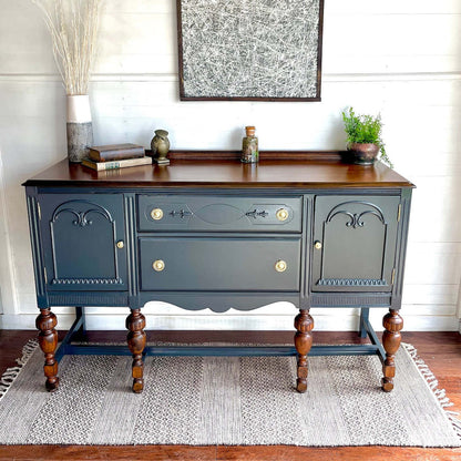Dark gray sideboard with wooden accents in a room with a rug and wall art.