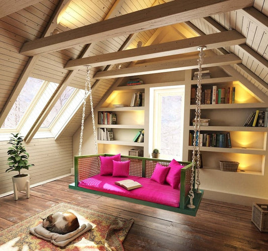 A green and pink French Garden Retreat Swing with handcrafted cane work, hanging indoors in a cozy setting with wooden beams and bookshelves in the background.