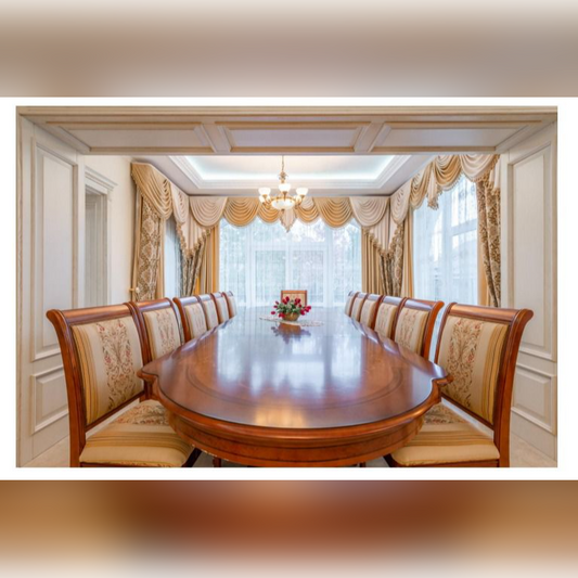 Dining room with a long wooden table and ornate chairs in a well-lit room.