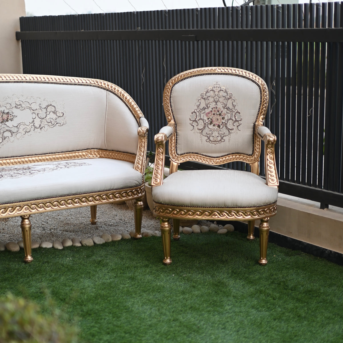 Decorative chair and sofa with gold frames and white cushions on a green surface.