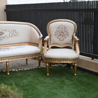Decorative chair and sofa with gold frames and white cushions on a green surface.