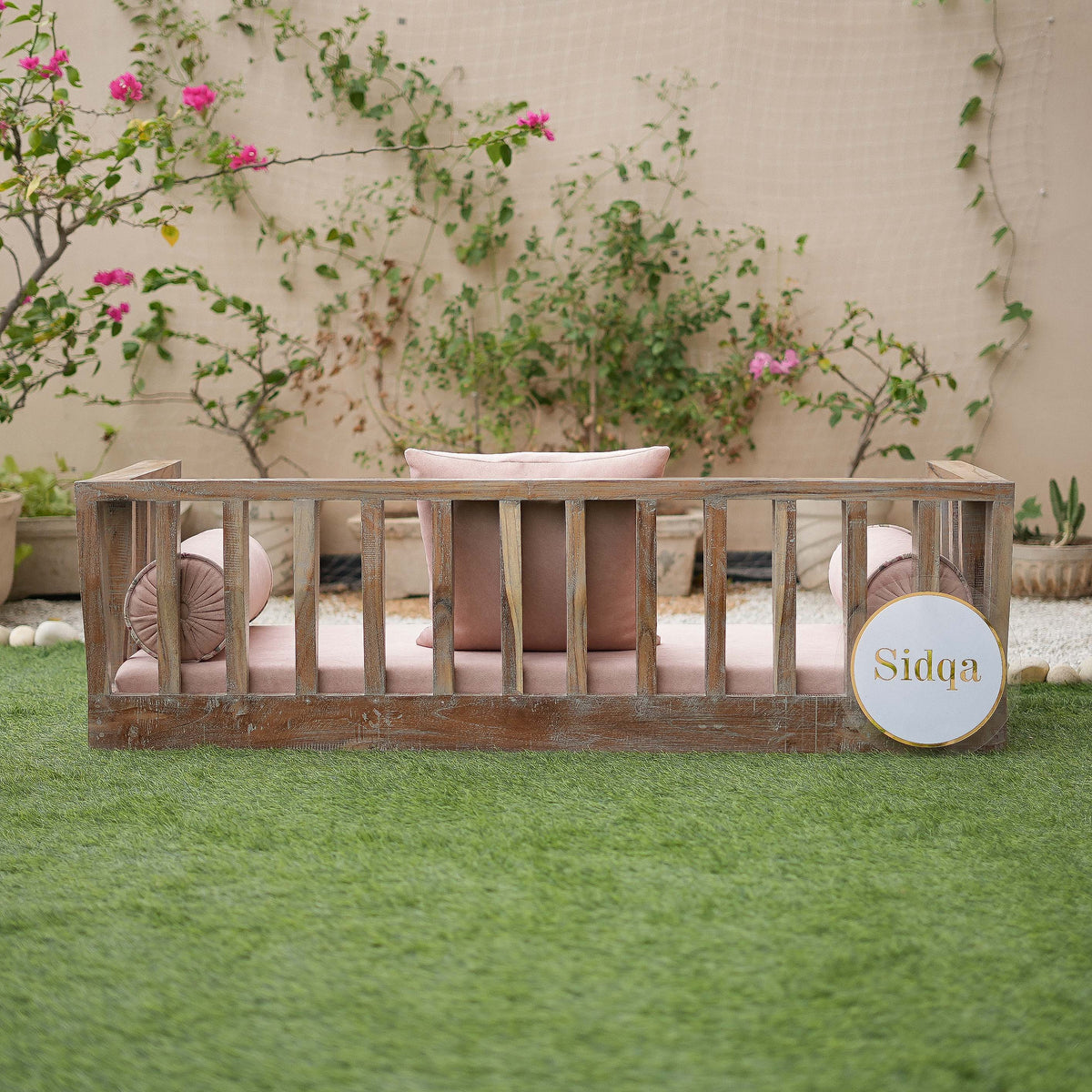 Wooden crib with pink bedding in a garden setting