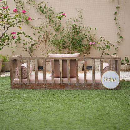 Wooden crib with pink bedding in a garden setting