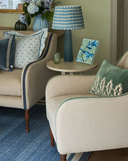 Living room with beige armchairs, decorative pillows, and a lamp on a side table.