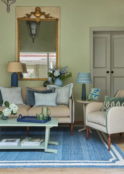 Living room with beige sofa, armchair, and decorative items on a blue rug.