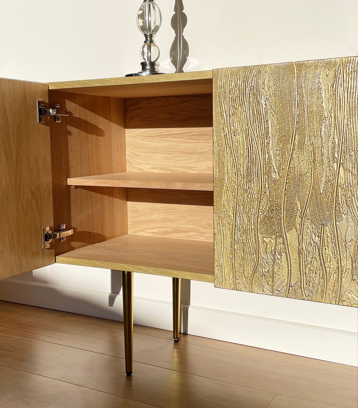Wooden cabinet with open door revealing shelves, on a wooden floor.