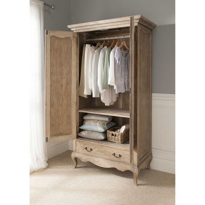 A wooden armoire with clothes hanging inside, featuring an open door, situated in a room with a light interior.