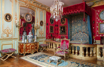 Opulent interior with red velvet canopy bed, ornate furniture, and decorative elements.