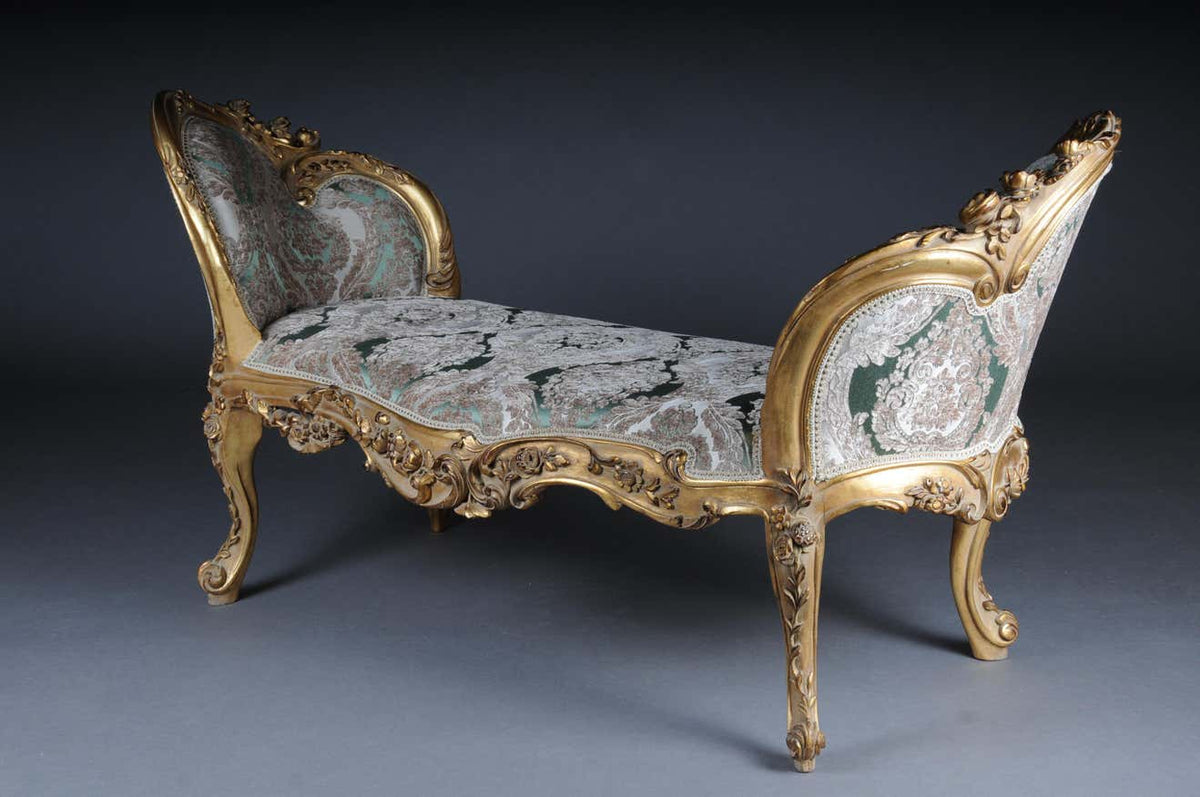 An ornate two-seater divan with antique gold accents and intricate heavy carving, upholstered in pastel green jacquard fabric.