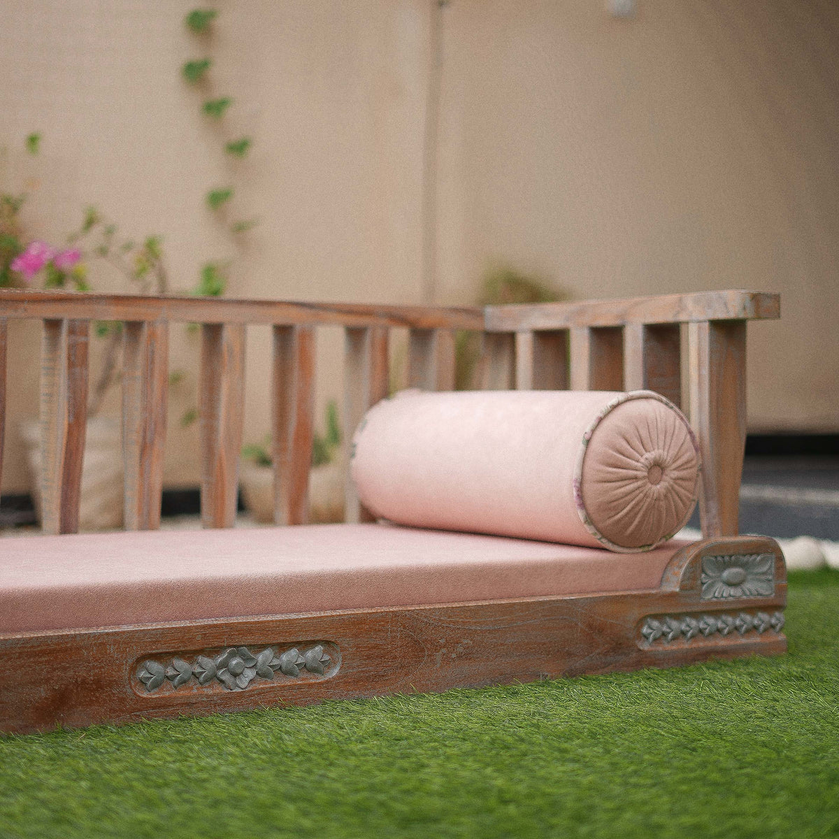 Wooden bench with pink cushion on grass