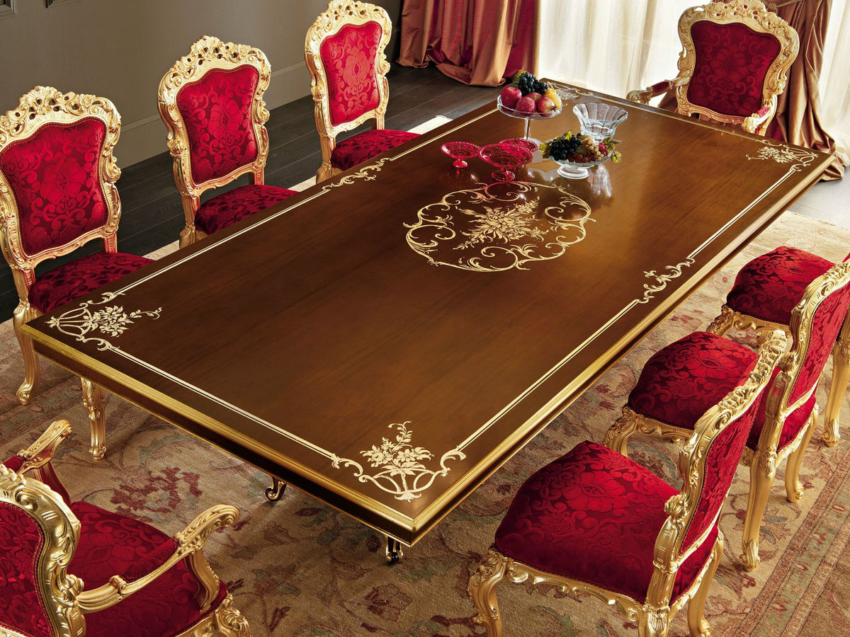 Dining table set with red chairs and gold accents in a formal dining room.