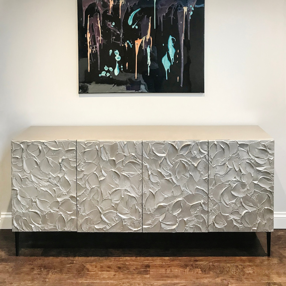 Textured silver cabinet with abstract painting above it