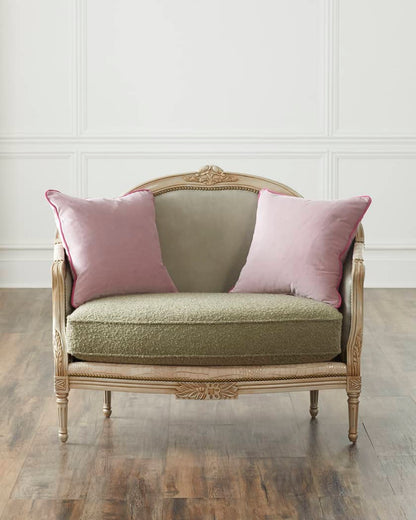 Vintage-style chair with pink cushions against a white paneled wall.