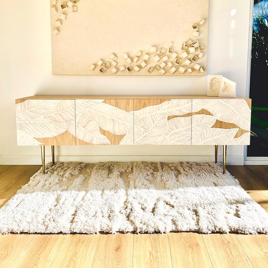 Wooden console table with decorative design in a room with a rug and wall art.