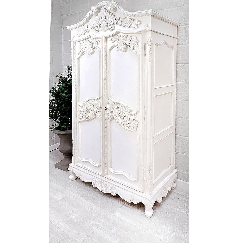 An ornate white wardrobe with floral carvings and a rounded top, set against a minimalist interior.