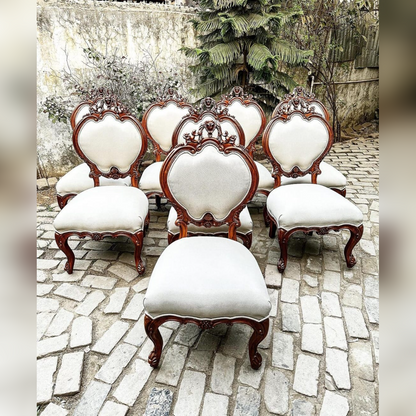 Set of ornate chairs with white cushions on a stone pathway