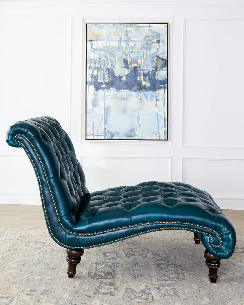Blue leather chaise lounge in a room with abstract art on the wall.