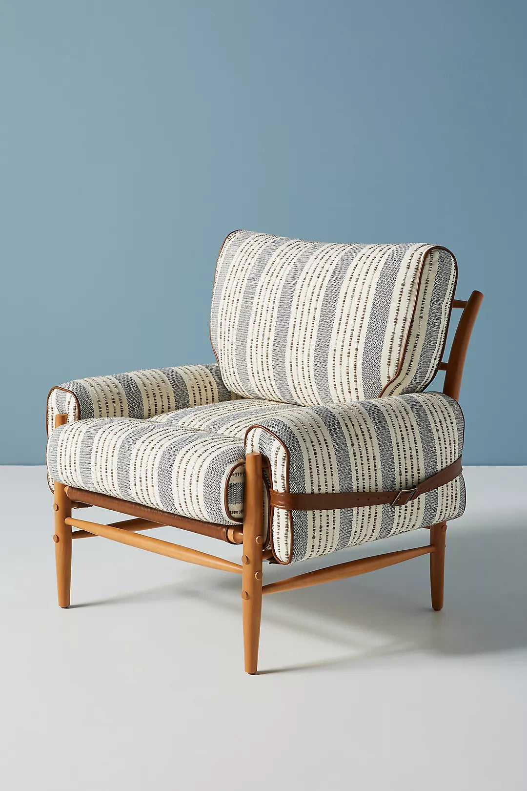 Patterned armchair with wooden frame against a blue wall