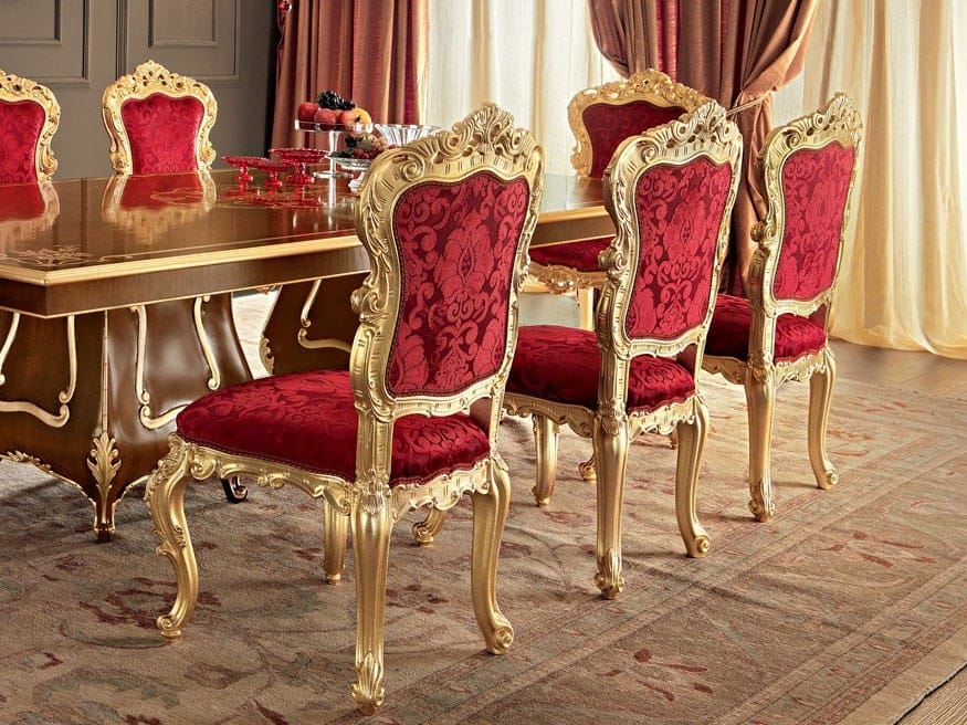 Dining table set with red chairs and gold frames in a formal setting.