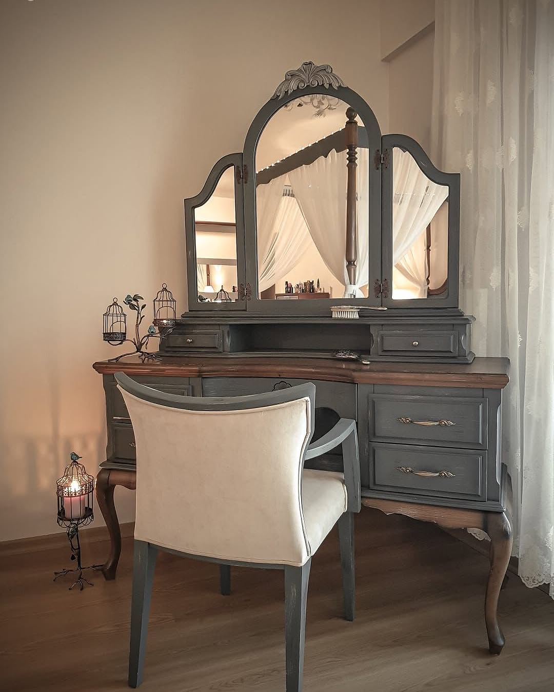 Dressing table with a large mirror and a chair in a room with curtains.