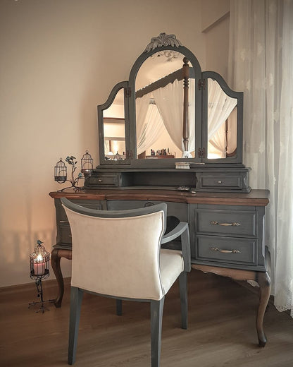 Dressing table with a large mirror and a chair in a room with curtains.