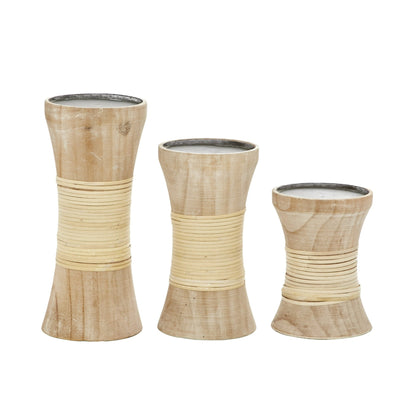A set of three graceflly tapered, beige colored candle stands made of natural bamboo with a teak wood base.