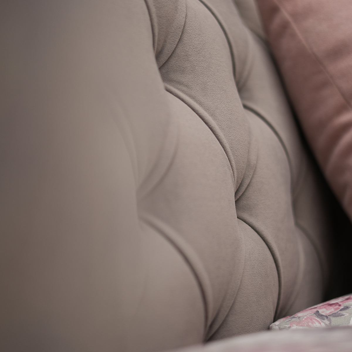 Close-up of a textured beige fabric surface with a blurred pink fabric in the background