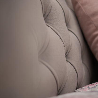 Close-up of a textured beige fabric surface with a blurred pink fabric in the background