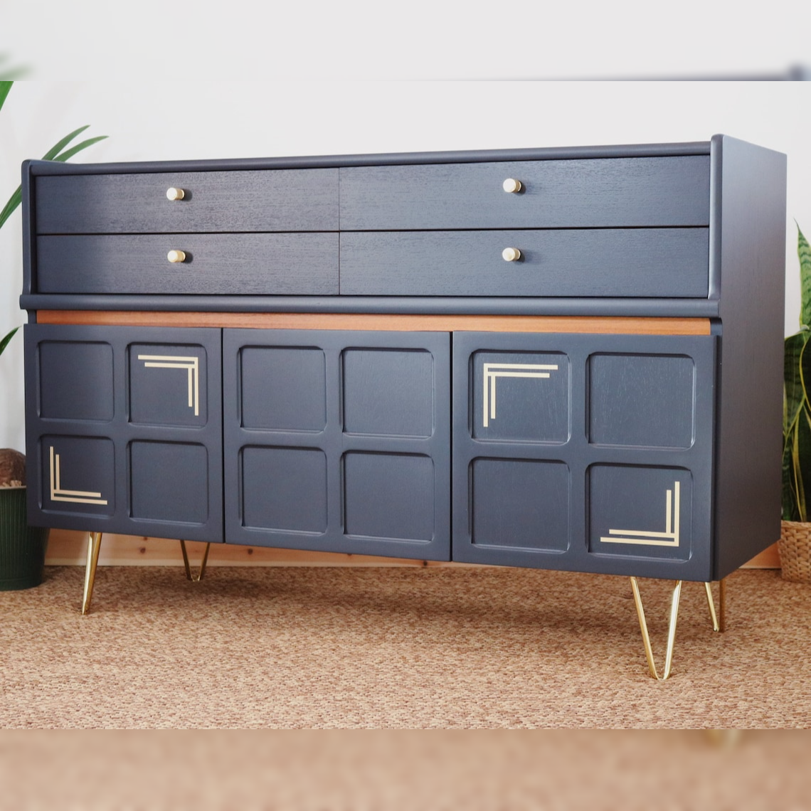 A sleek midnight blue buffet with gold handles and matte-metal feet, featuring a tailored silhouette with sculptural details.