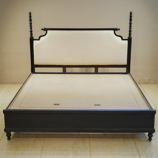 Black metal bed frame on a beige floor with a plain wall background