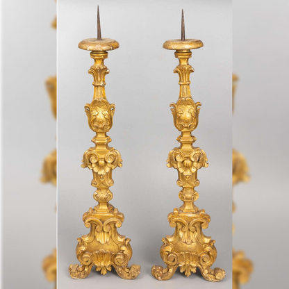 Pair of ornate gold candlesticks on a light gray background