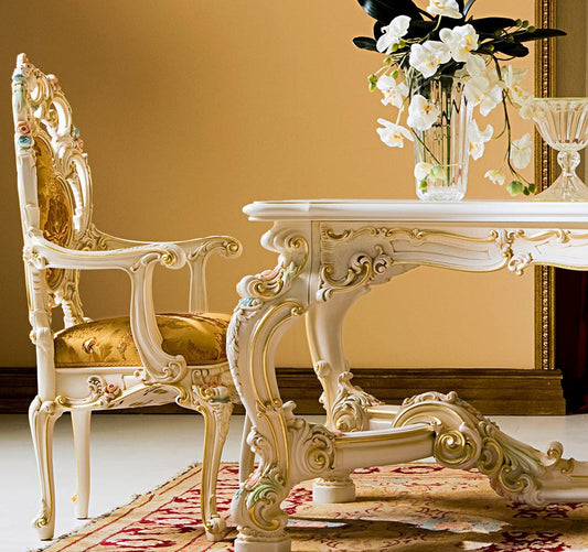 Ornate white table and chair set with gold accents in a room with a yellow wall.