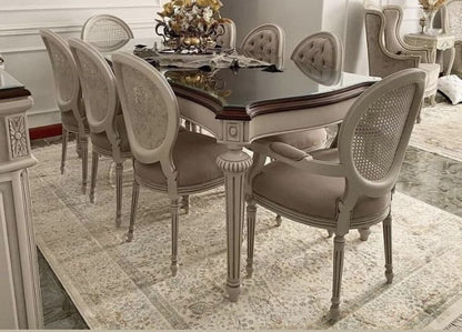 Dining room with a large table and ornate chairs on a patterned rug.